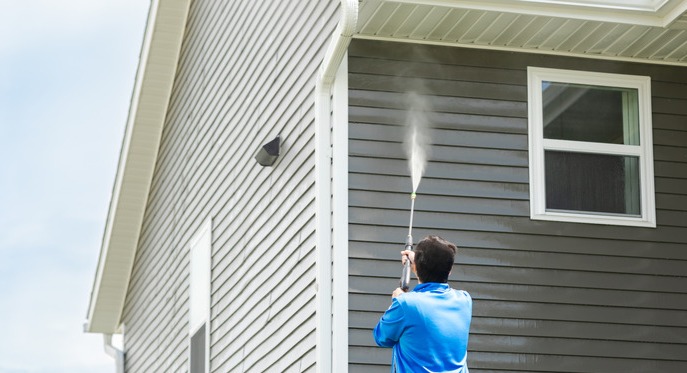 A So Clean Solutions technician applies cleaning solution to the vinyl siding of a customer's home.