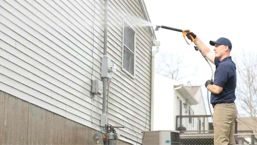 A So Clean Solutions technician applies cleaning solution to the vinyl siding of a customer's house.