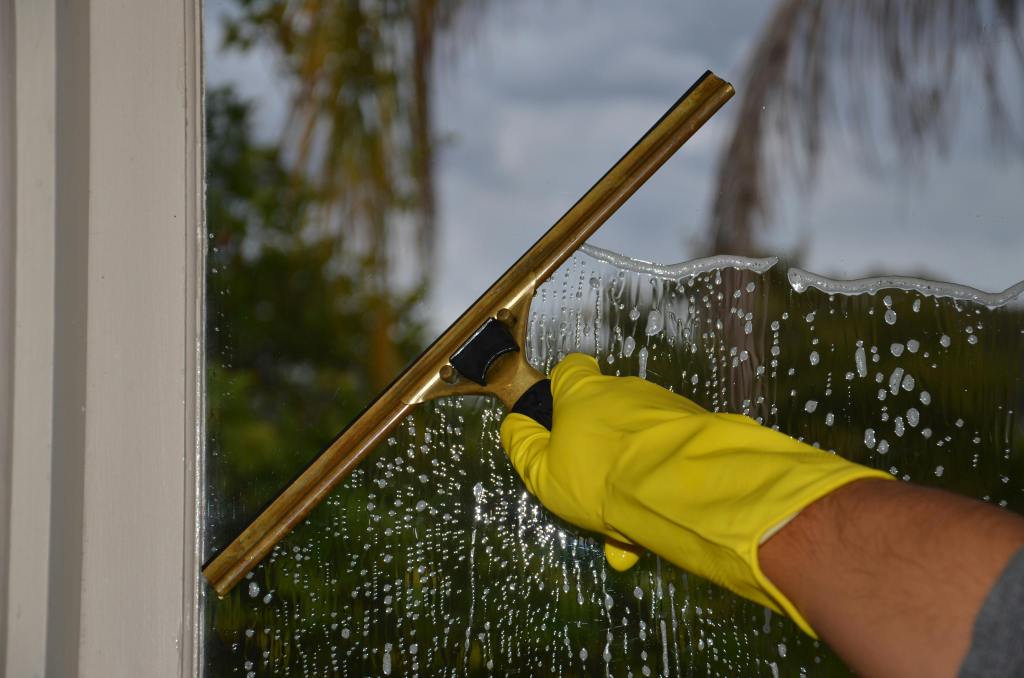 A So Clean Solutions exterior cleaning services technician uses a squeegee to perform professional window cleaning.