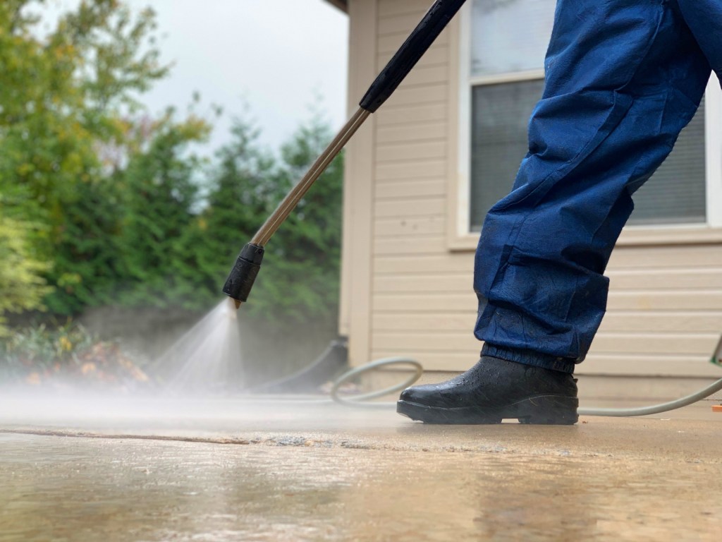 A So Clean Solutions technician uses a pressure washer to clean a customer's driveway.