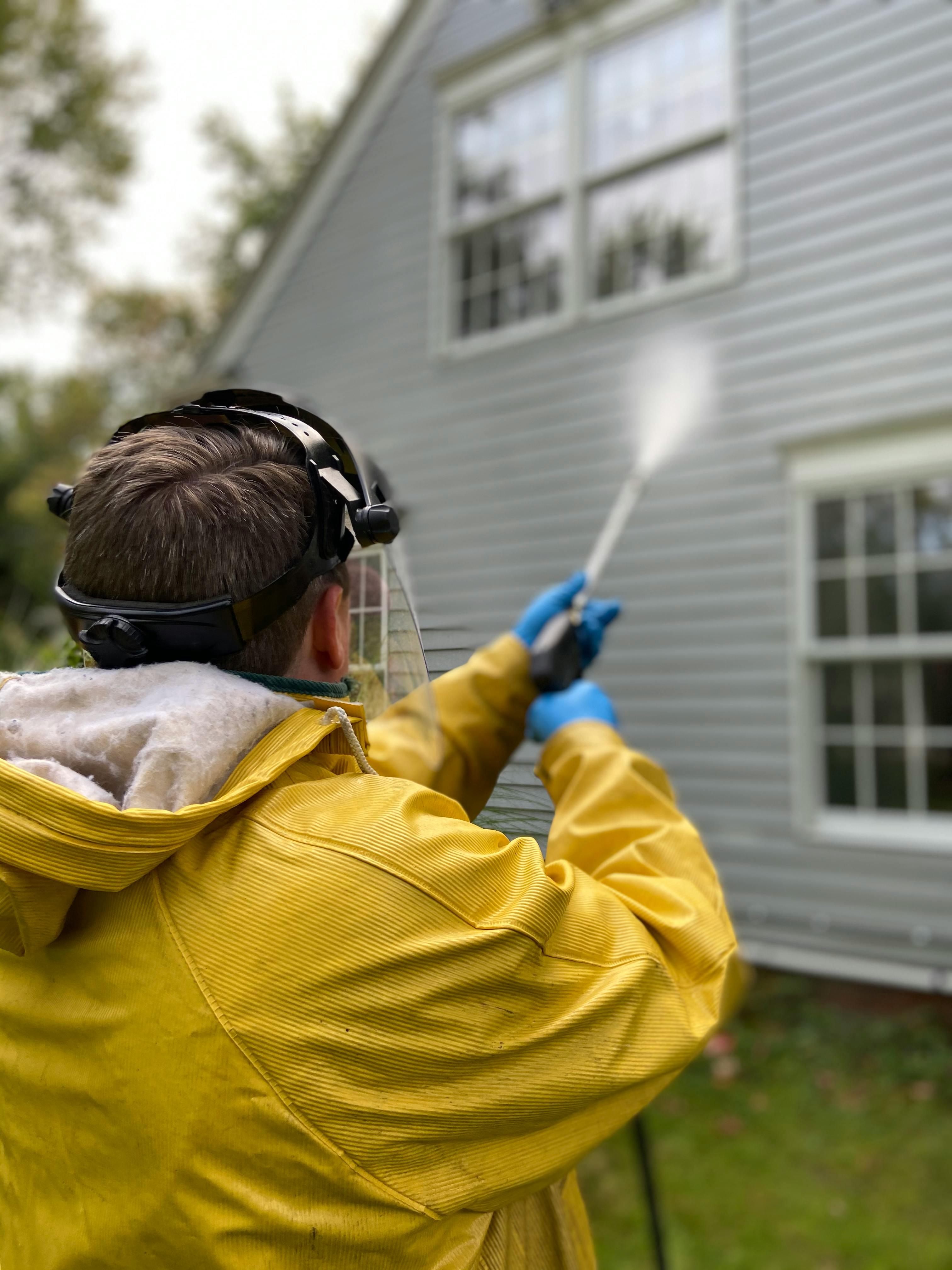 A So Clean Solutions technician performs a rinse on the vinyl siding of a customer's home during a soft wash cleaning service.