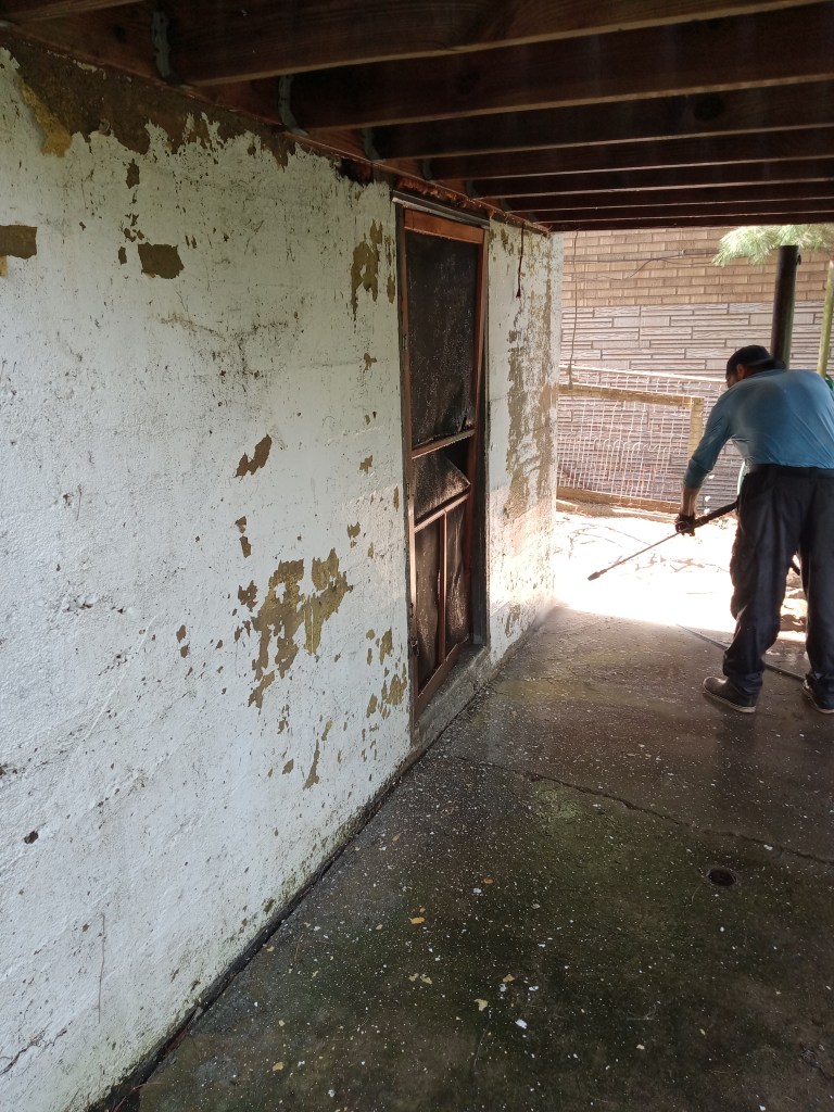 A So Clean Solutions technician uses a turbo tip to pressure wash a block wall foundation prior to a painting project.