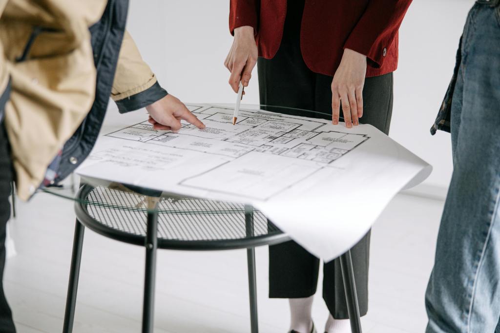 A property manager reviews a building floor plan with two potential tenants.