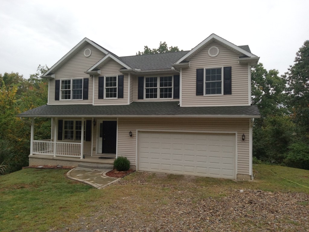 A Pittsburgh-area home in need of exterior cleaning for tiger-striping on gutters, organic growth on roof shingles and siding, and hard-water stained windows.